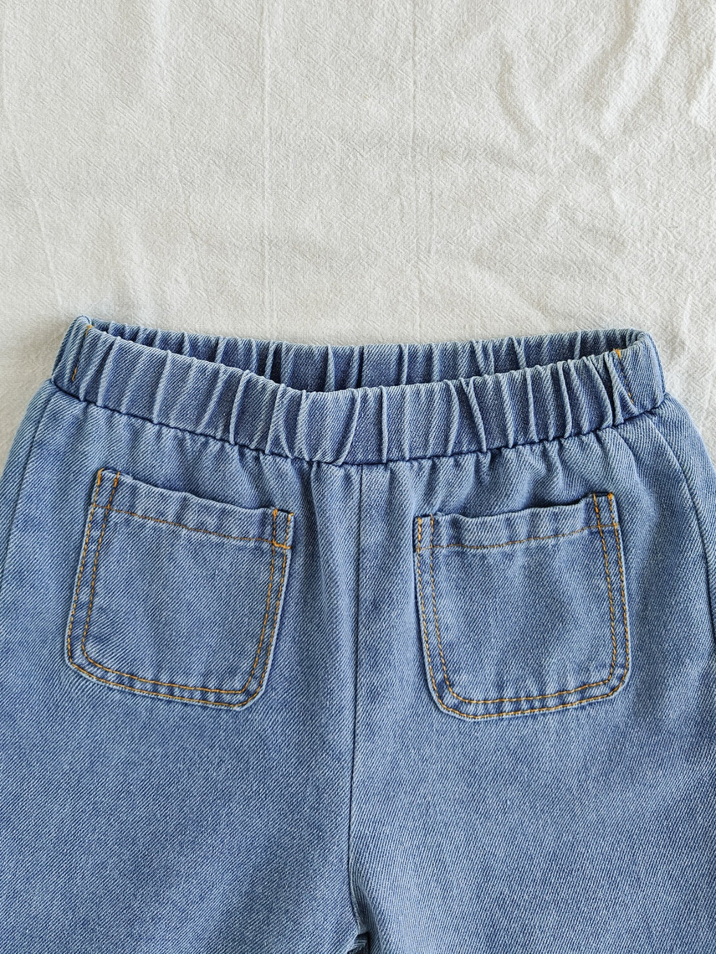 طقم ملابس بناتي ربيعي/خريفي مكون من ثلاث قطع: جاكيت جينز أزرق فاتح بأكمام طويلة، تيشيرت أبيض بأكمام قصيرة، وبنطال جينز.