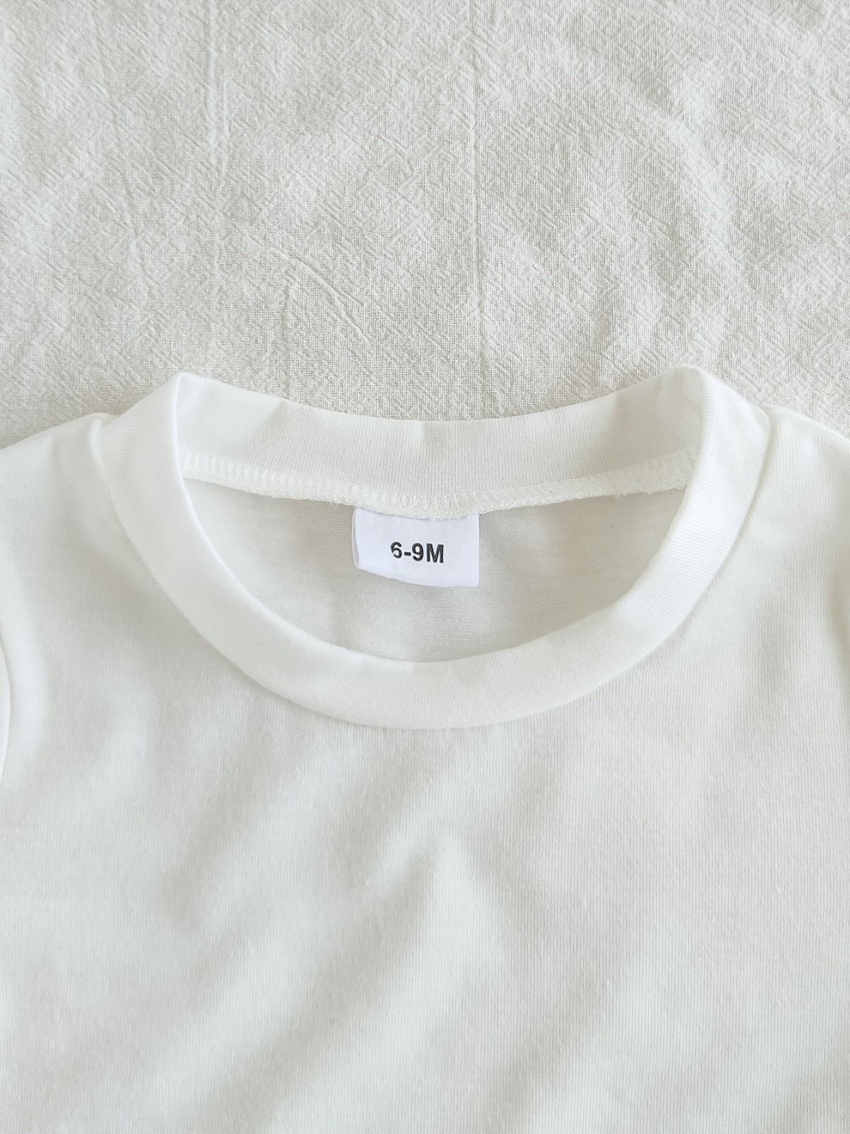 طقم ملابس بناتي ربيعي/خريفي مكون من ثلاث قطع: جاكيت جينز أزرق فاتح بأكمام طويلة، تيشيرت أبيض بأكمام قصيرة، وبنطال جينز.