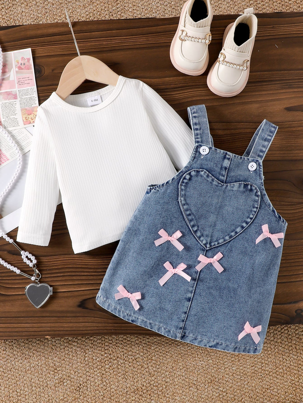 طقم مكون من قطعتين: تيشيرت بأكمام طويلة وبنطال جينز مزين بجيب على شكل قلب وفيونكة.