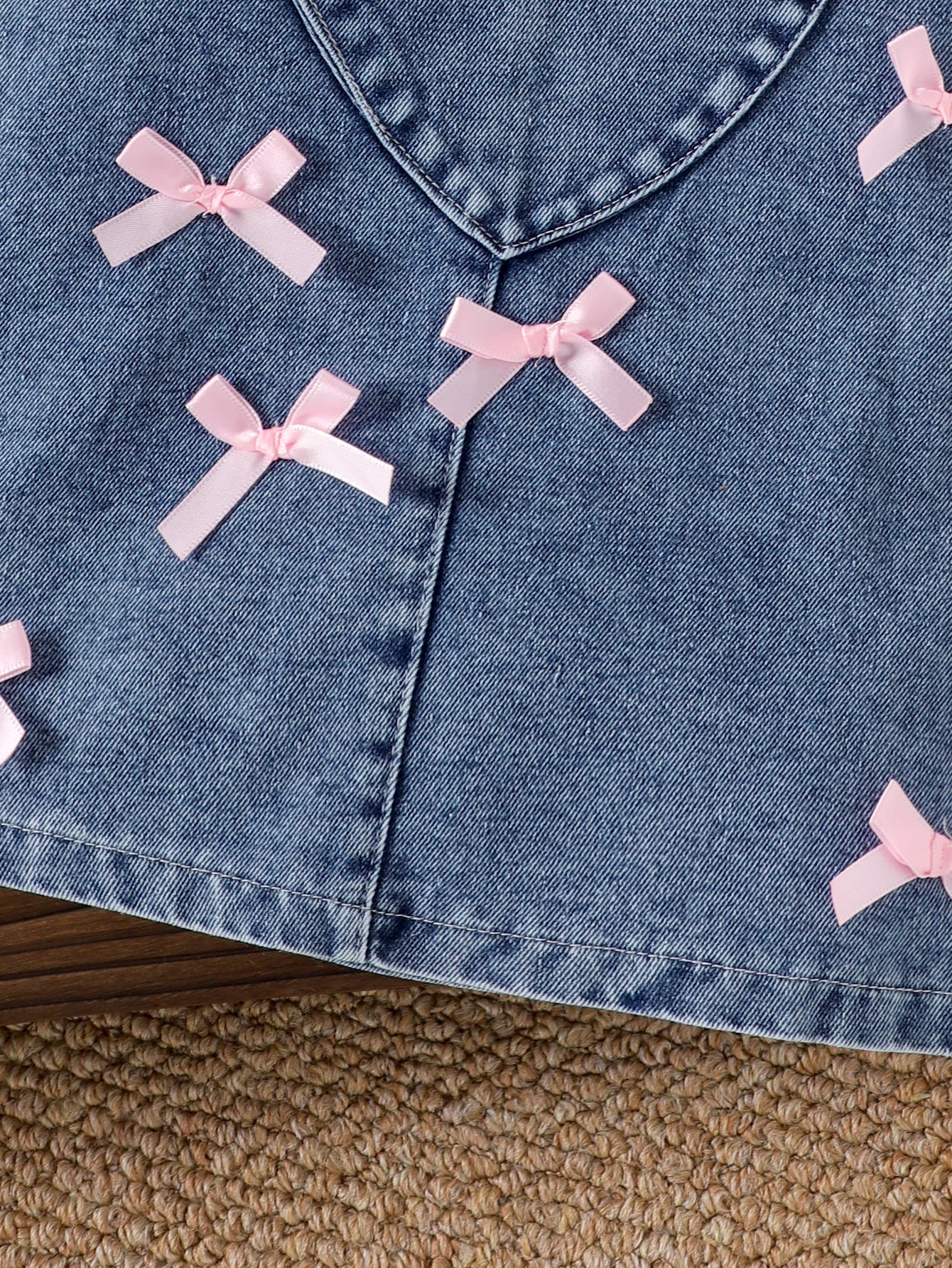 طقم مكون من قطعتين: تيشيرت بأكمام طويلة وبنطال جينز مزين بجيب على شكل قلب وفيونكة.