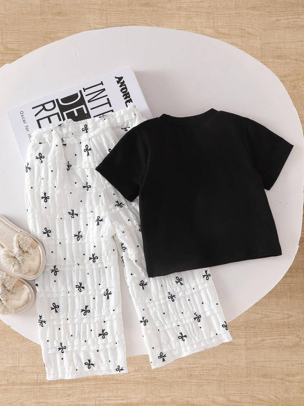 طقم صيفي مكون من قطعتين للبنات الصغيرات: تيشيرت أسود بأكمام قصيرة وبنطال أبيض مزين بفيونكة